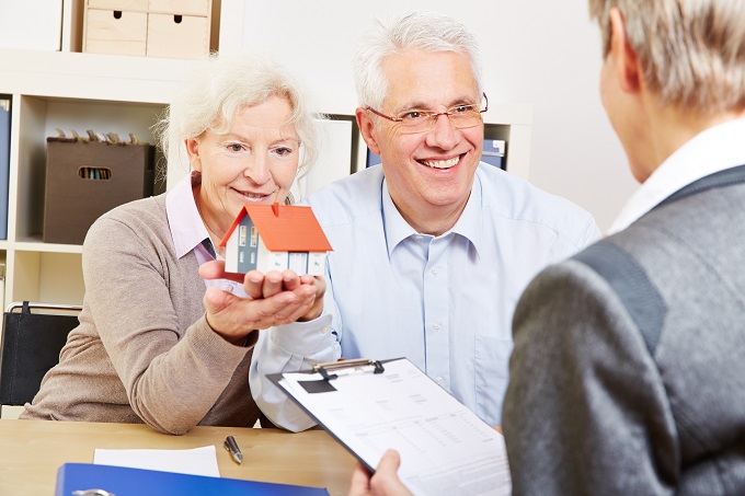 Happy senior couple with little house buying real eastate in off